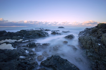 gorgeous sunset long exposure on the beach with sea waves and cliffs