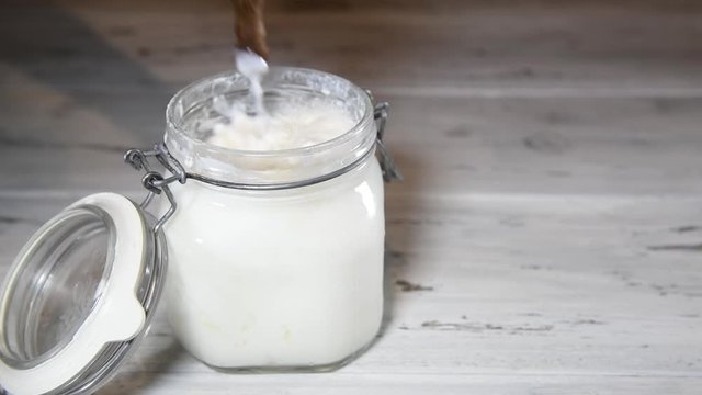 Close up of fresh homemade fermented beverage kefir in a jar, a female hand mixing the kefir for filtering kefir grains from kefir, concept of natural fermented food and intestinal health