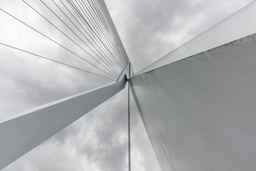 Wide angle view of the center pillar and cables of the Erasmus Bridge as seen from below, against a...