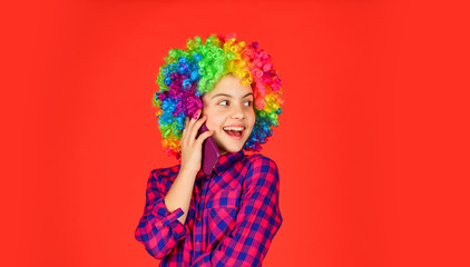 positive and cheerful. childhood happiness. kid looking funny in rainbow wig hair. hair dyeing at hairdresser. child having fun. happy birthday party. small girl colorful wig speak on phone.