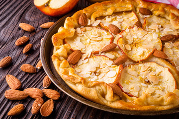 crispy apple galette with almonds on rustic wooden background