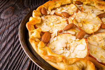 crispy apple galette with almonds on rustic wooden background