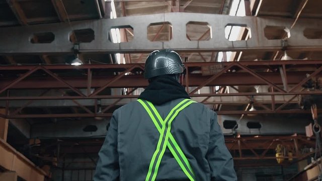 Factory worker in a hard hat is walking through industrial facilities. Slow motion Full HD Сamera flight