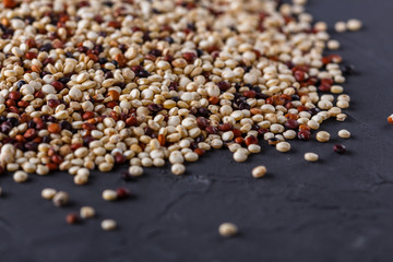 mix of quinoa grains on a dark stone background