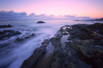 gorgeous sunset long exposure on the beach with sea waves and cliffs