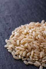 raw brown rice on a dark stone background