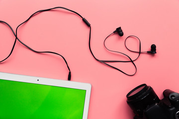 headphones with a white tablet and photo camera on a pink background