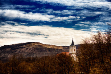 Eine Kirche mit Turm und Uhr, und ein Steinabbruch