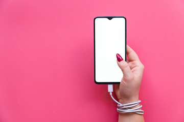 Top view woman hand have modern smartphone whith blank screen on pink background. Dependences on social networking sites, internet and gadgets .