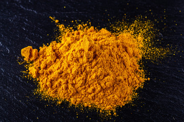 natural turmeric powder on a dark stone background