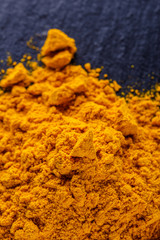 natural turmeric powder on a dark stone background