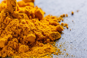 natural turmeric powder on a dark stone background
