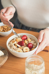 Oatmeal porridge with fruits and berries for healthy breakfast. Woman eating vegetarian breakfast porridge oats