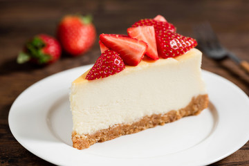 Cheesecake with strawberries on plate, wooden table background