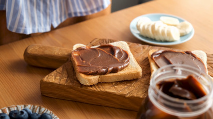 Obraz na płótnie Canvas Chocolate nut butter toast on a wooden board. Tasty breakfast or lunch sandwich