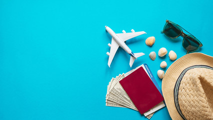 Travel accessories and objects on a blue background with a top view and copy space. Airplane and passport, money, hat, ticket. Travel background for travel agency banner advertisement. Flatlay
