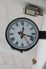 Wall clock with black hour and minute hands and a red second at the station
