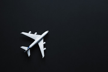 Toy plane on a black background with top view and copy space. Travel  concept.