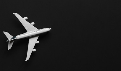 Fototapeta na wymiar Toy plane on a black background with top view and copy space. Travel concept background.