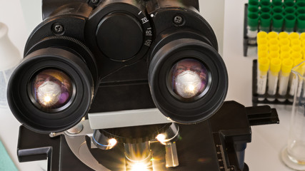 Laboratory medical microscope ocular lens with mirroring a man face in white surgical mask. Lab...