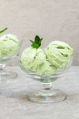 Homemade green avocado ice cream decorated with mint leaves on concrete background