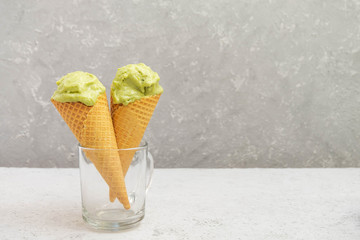 Waffle cones with healthy green avocado ice cream on neutral grey background