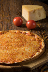 Pizza, tomatoes, cheese, olive oil on a wooden table