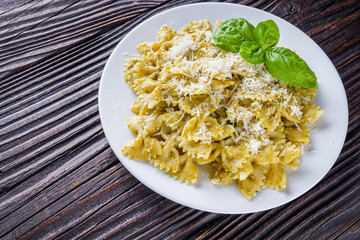 Delicious farfalle pasta with pesto sauce on wooden rustic background