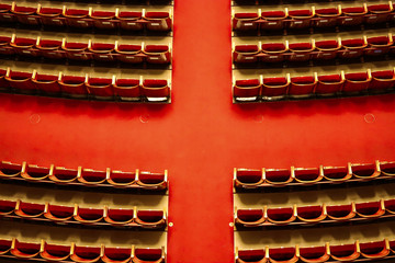 Central hall of the vienna theater with red cross-shaped carpet and armchairs on the sides without people.