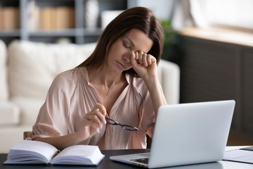 Overwhelmed unhappy young woman taking off glasses, rubbing eyes, feeling exhausted, working...