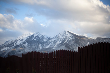 Wooden fence at the house in the mountains. Toothed fence on the background of a hillside. The fence around the building made of wood.