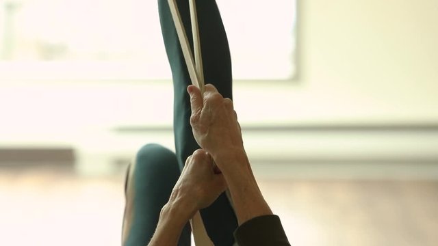 Selective focus of female leg exercising using resisting loop band with left and right movements while practice chair pose to improve flexibility