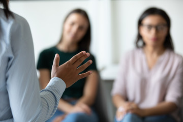 Close up of confident female speaker stand hold lead meeting with diverse colleagues, successful...