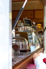 A portrait of a market stall with cake and other pastries inside. The stall is filled with glass domes to cover up the food in the market truck.