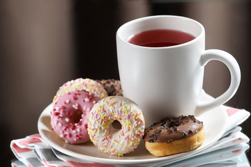  White tea cup with donuts on a white plate.