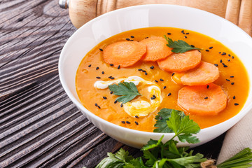 pumpkin carrot cream soup on rustic wooden background