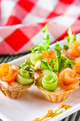 delicious snack tartlets on rustic wooden background