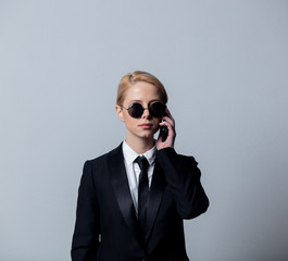 businesswoman in a classic black business suit and sunglasses talking on mobile phone