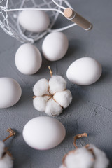 White eggs in a metal basket and cotton flowers. Easter background.