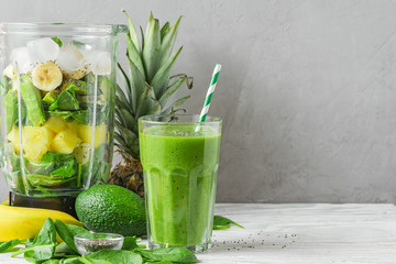 Blender with fresh ingredients to making healthy detox smoothie with glass of green prepared drink...