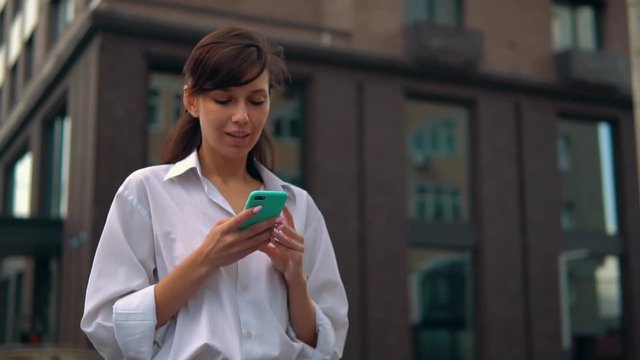 happy student scrolling touch screen on mobile shaping post in social media female walking in city slow motion