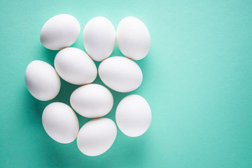 white chicken eggs on green pastel background