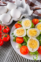 salad with boiled chicken eggs and cherry tomatoes on a wooden rustic background