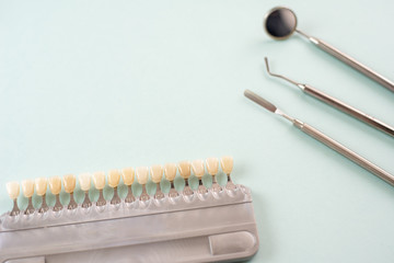Color palette of different shades of teeth and dental tools on a blue background. Teeth whitening...