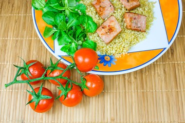 Barley porridge with sausage and vegetables . tomatoes background