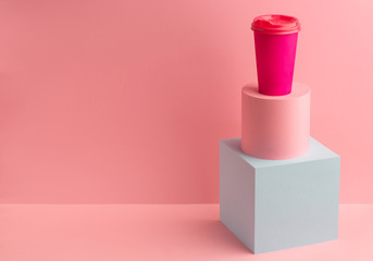 Bright coffee paper cup on pink background with copy space