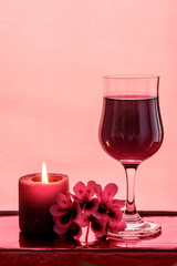 Wine, candle and red flower setting with a blush background