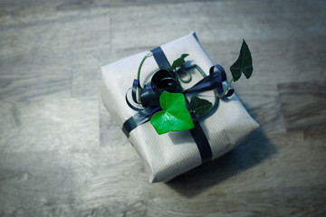Small cute stylish wrapped parcel. Ivy decorated by the ribbon.