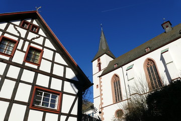 Fototapeta na wymiar Sankt-Mariä-Himmelfahrt-Kirche mit Fachwerkhaus in Blankenheim an der Ahr