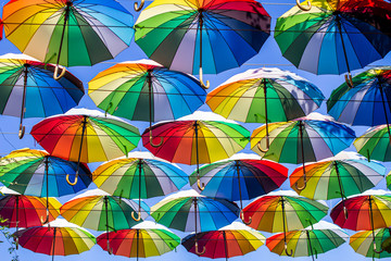 Fototapeta na wymiar Colorful umbrellas Blue, green, red, rainbow umbrellas background Street with umbrellasin the sky Street decoration.
